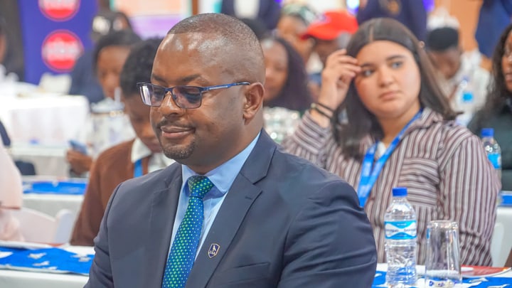 A guest in a suit seated at a table among the event audience.