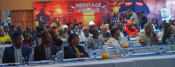 Audience members seated at tables in the event hall.