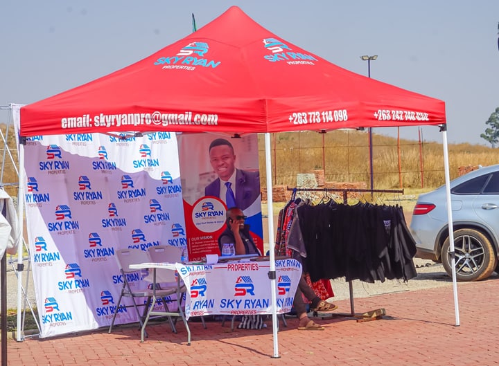 A red exhibition canopy with printed banners and garments on a display rail.