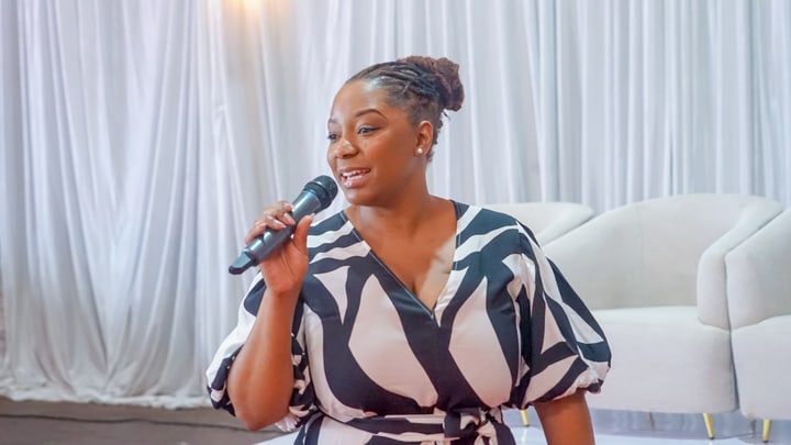 A seated panel participant speaks into a handheld microphone.