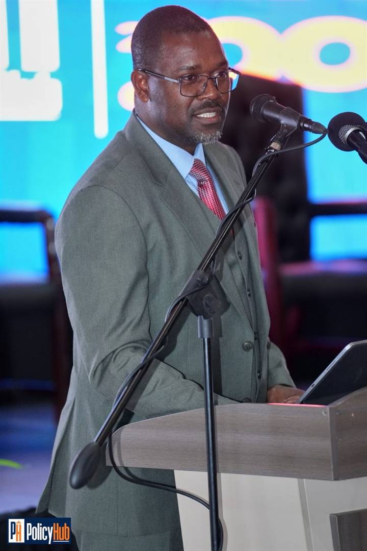 Speaker in a suit addressing the Expo at a microphone